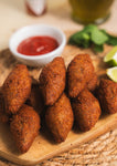 A plate of 12 golden-brown crispy Brazilian kibe croquettes served hot with fresh mint leaves and lemon wedges.