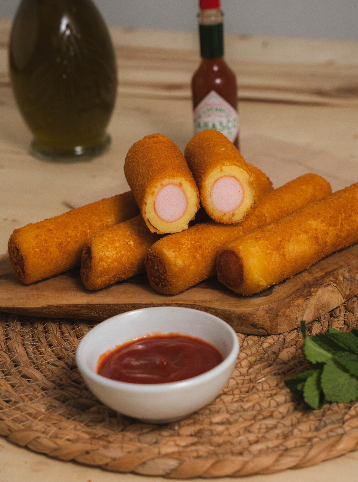 A golden-crisp breaded Brazilian sausage roll cut in half showing the savoury dough layer and the pork sausage filling inside.