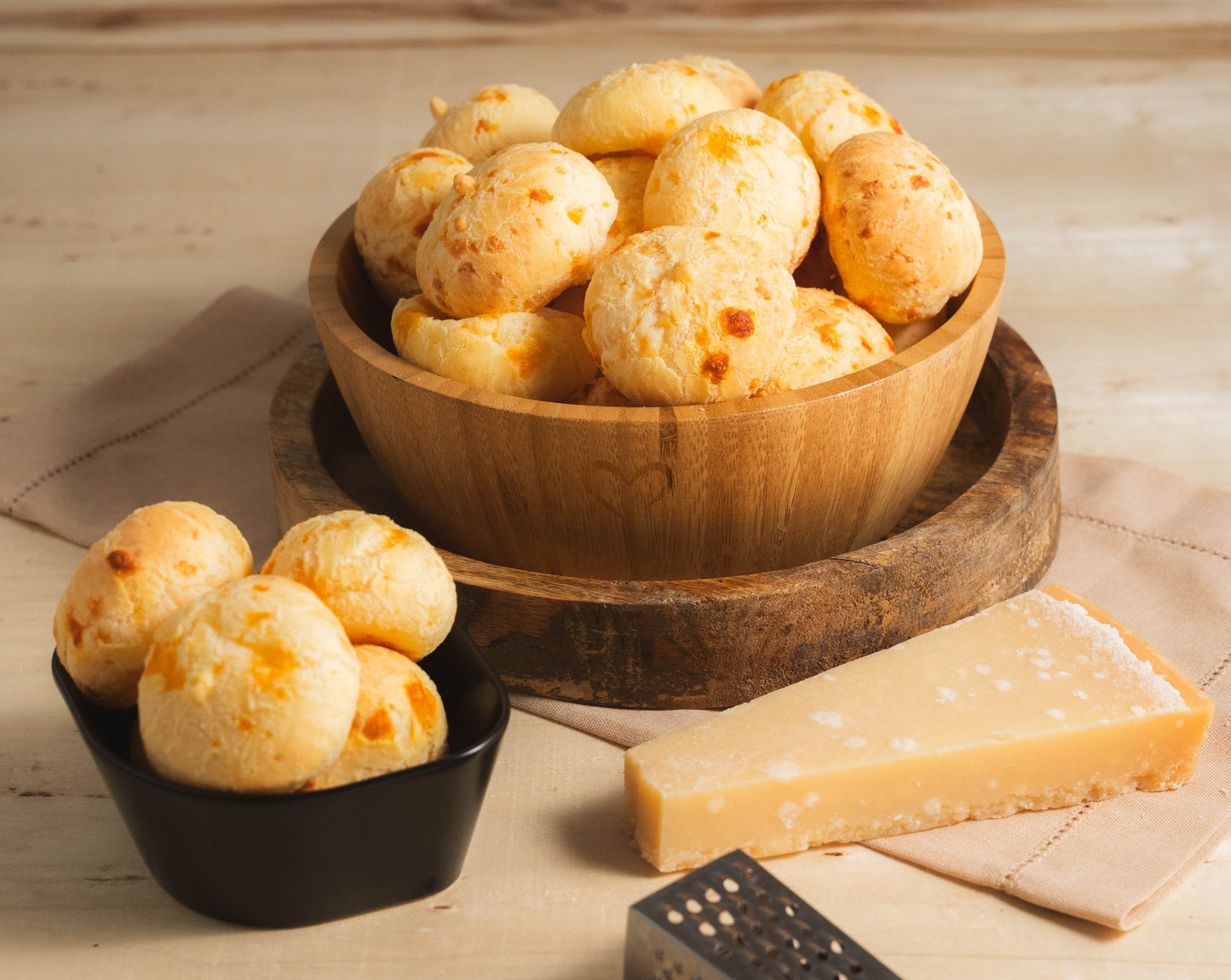 A serving bowl filled with baked, golden-crisp mini Brazilian cheese breads showing a fluffy texture, perfect for party catering.