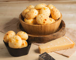 A serving bowl filled with baked, golden-crisp mini Brazilian cheese breads showing a fluffy texture, perfect for party catering.
