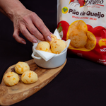 A serving bowl filled with baked, golden-crisp mini Brazilian cheese breads showing a fluffy texture, perfect for party catering.