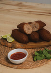 Golden-brown crispy Big Kibe croquette served hot on a plate, seasoned with fresh mint and traditional spices.