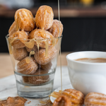 Churros is filled with a delicious Dulce de Leche Close-up of golden-brown crispy churros dusted with sugar, showing a rich and melted Dulce de Leche caramel filling bursting inside.
