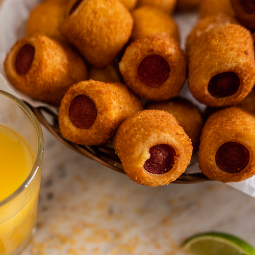 A party platter filled with golden mini Brazilian sausage rolls served hot, perfect for kids' parties and catering.